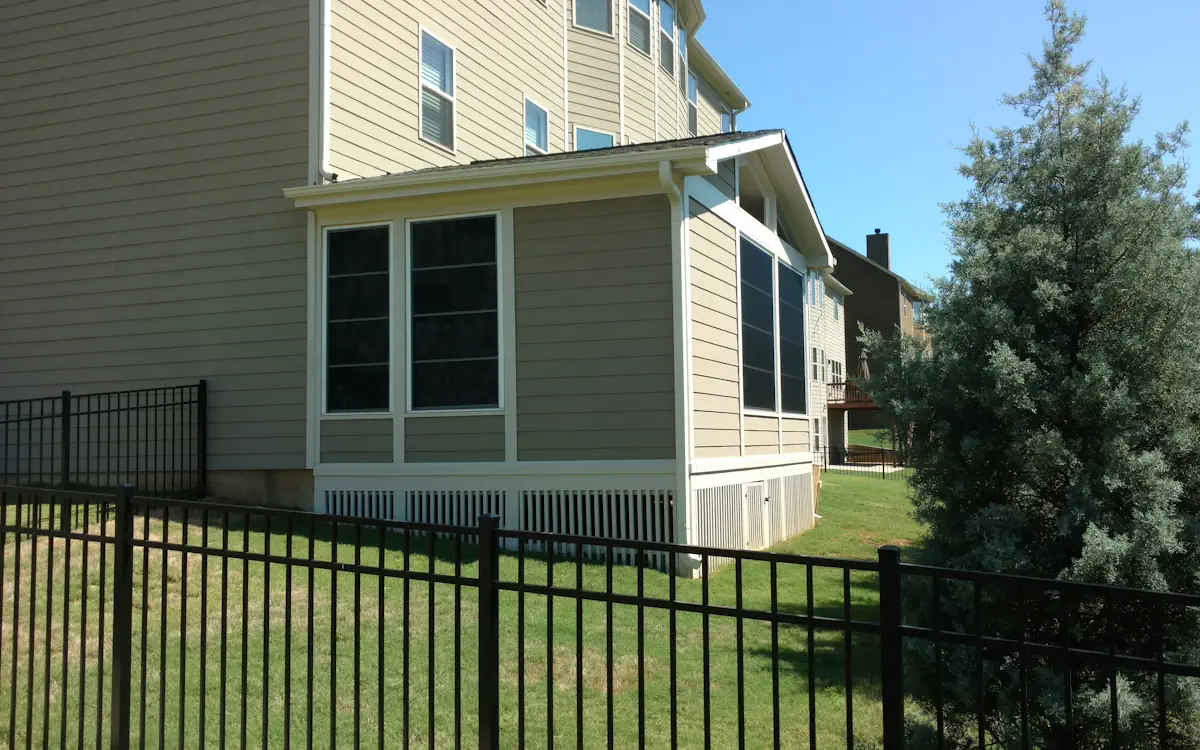 Beige sunroom with a gabled roof, large sunroom windows with grid patterns, solid lower panels, and exterior siding that matches the home.