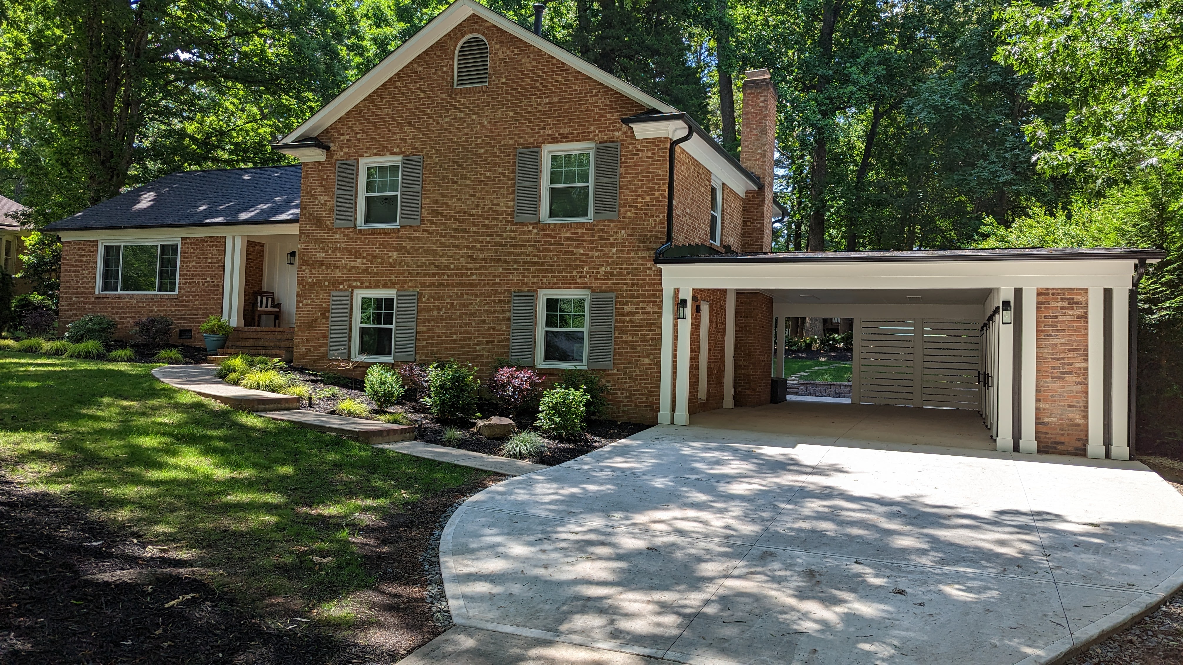 The brick split-level, period-inspired carport and curved concrete driveway come together as one composition.