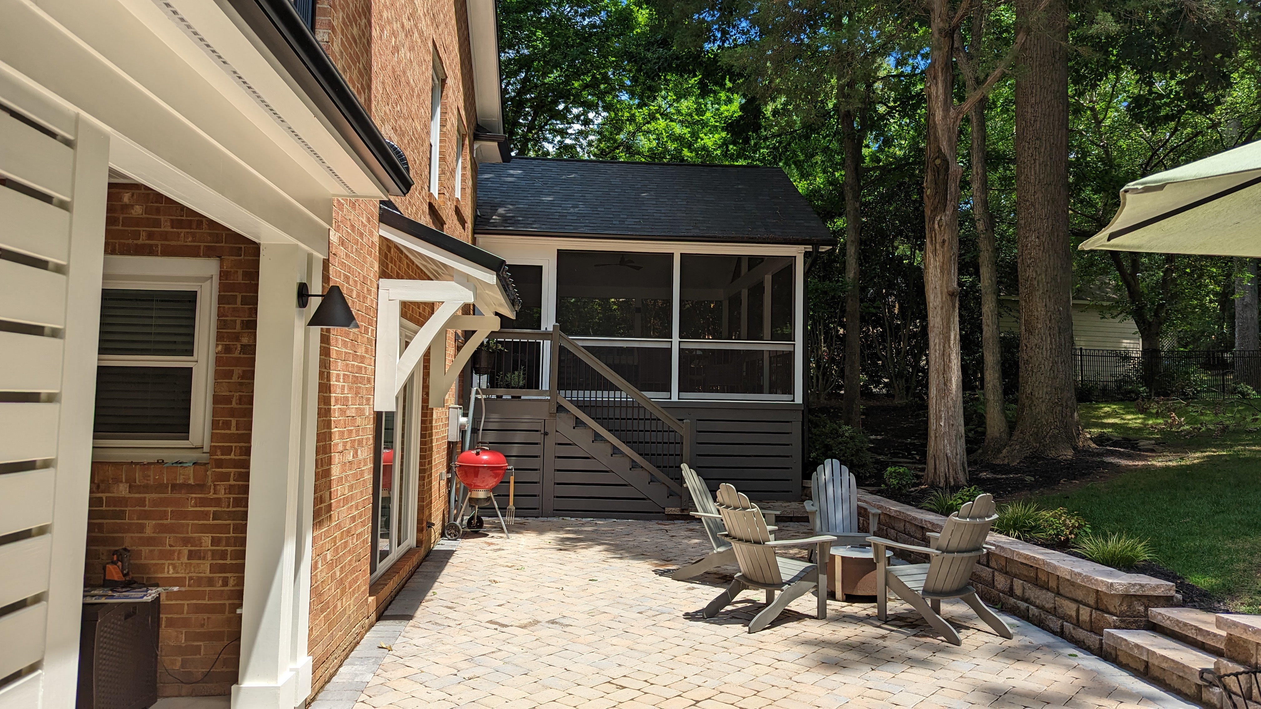 The sliding patio door sits beneath a bracket-supported standing-seam metal roof overhang.