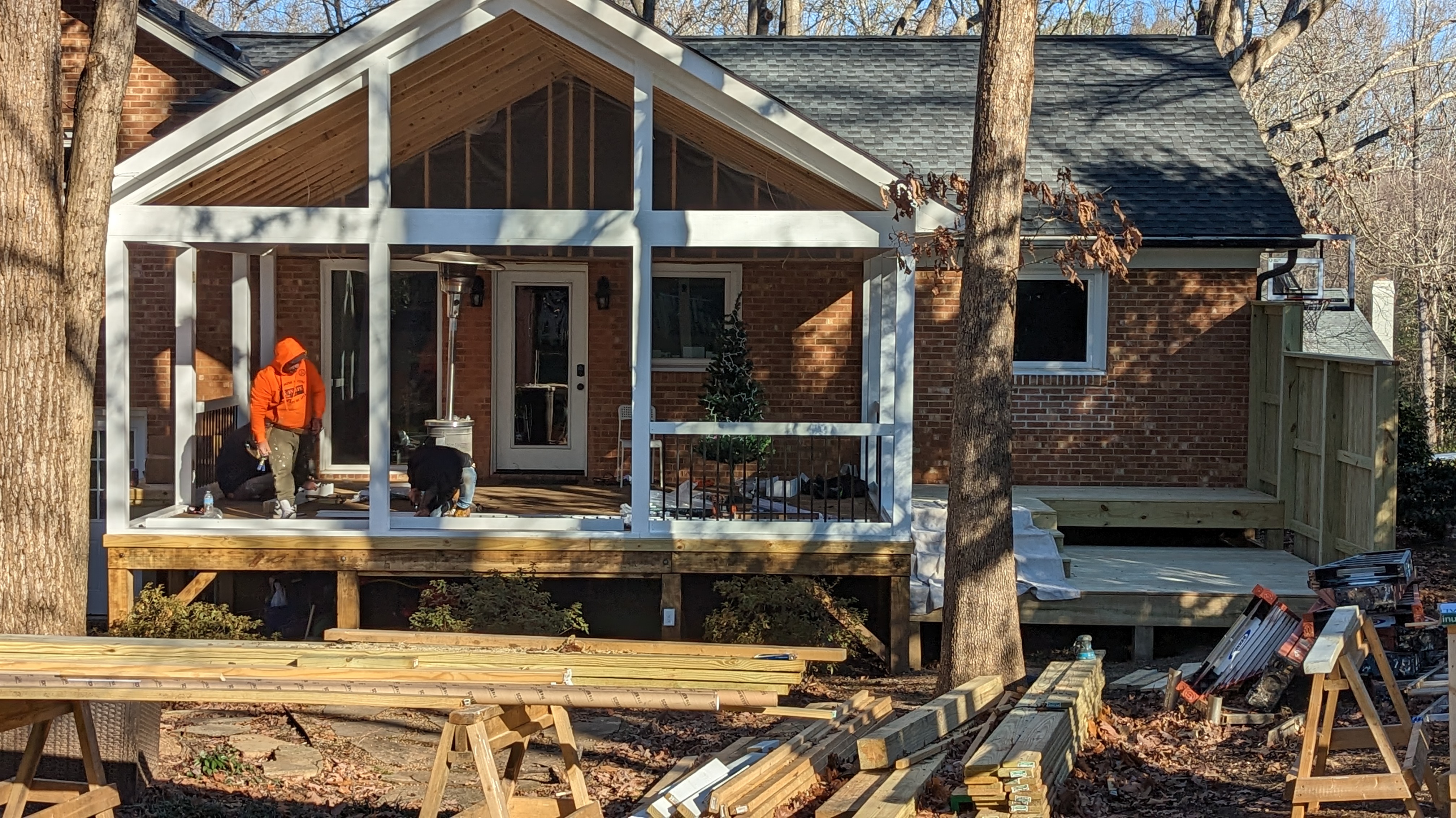 The crew works on the porch framing, railings and gable details.