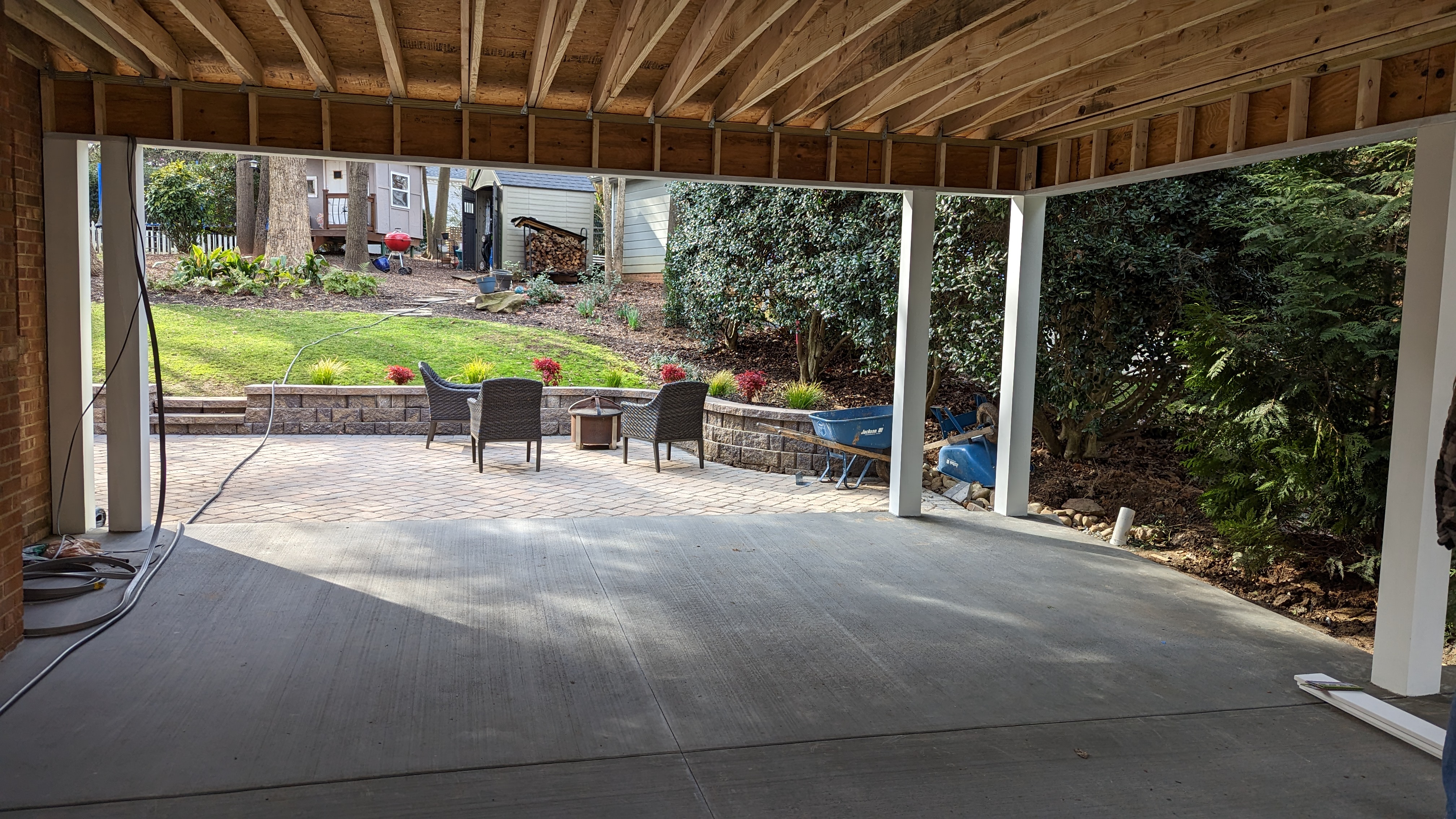 The new concrete floor is in place beneath the open carport framing.