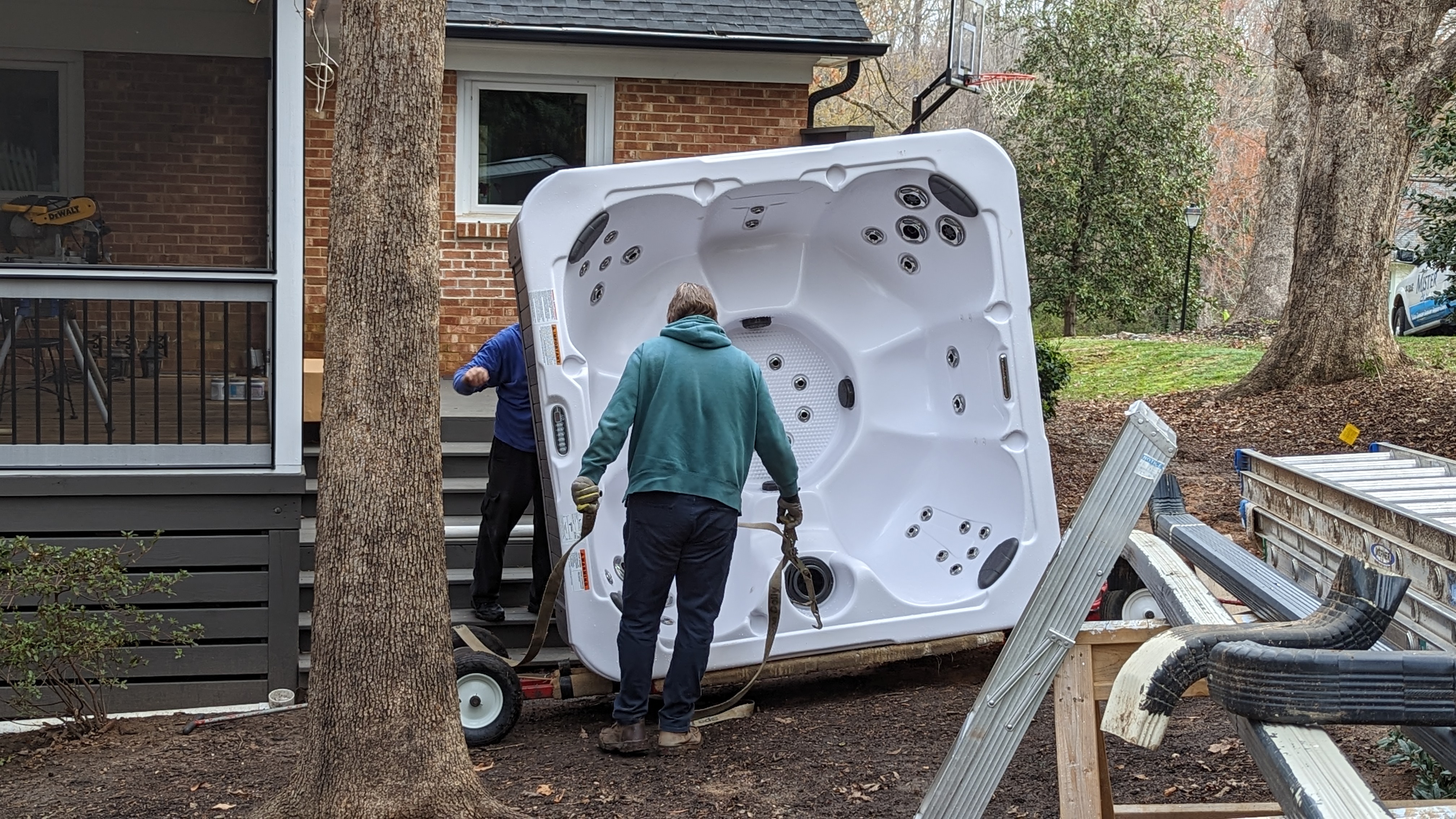 The delivery crew maneuvers the hot tub onto the spa deck.