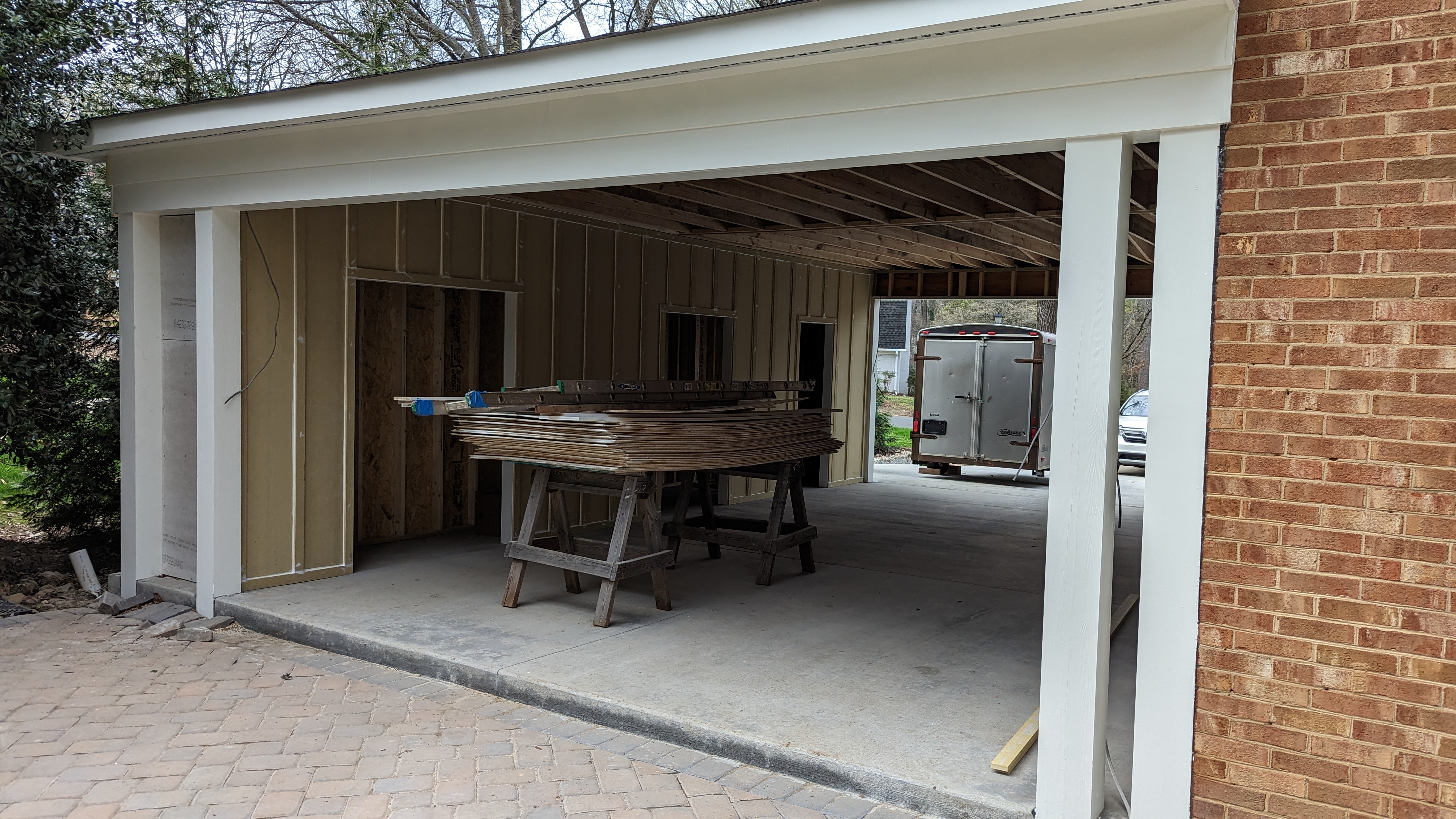 Storage openings are framed beneath the carport roof.