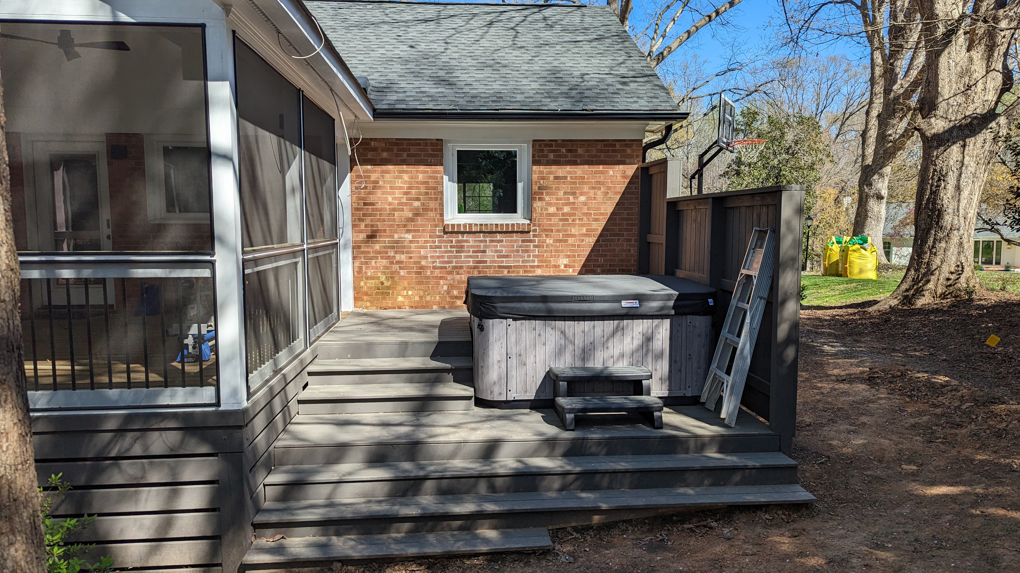 The hot tub is installed beside the screened porch and privacy wall.