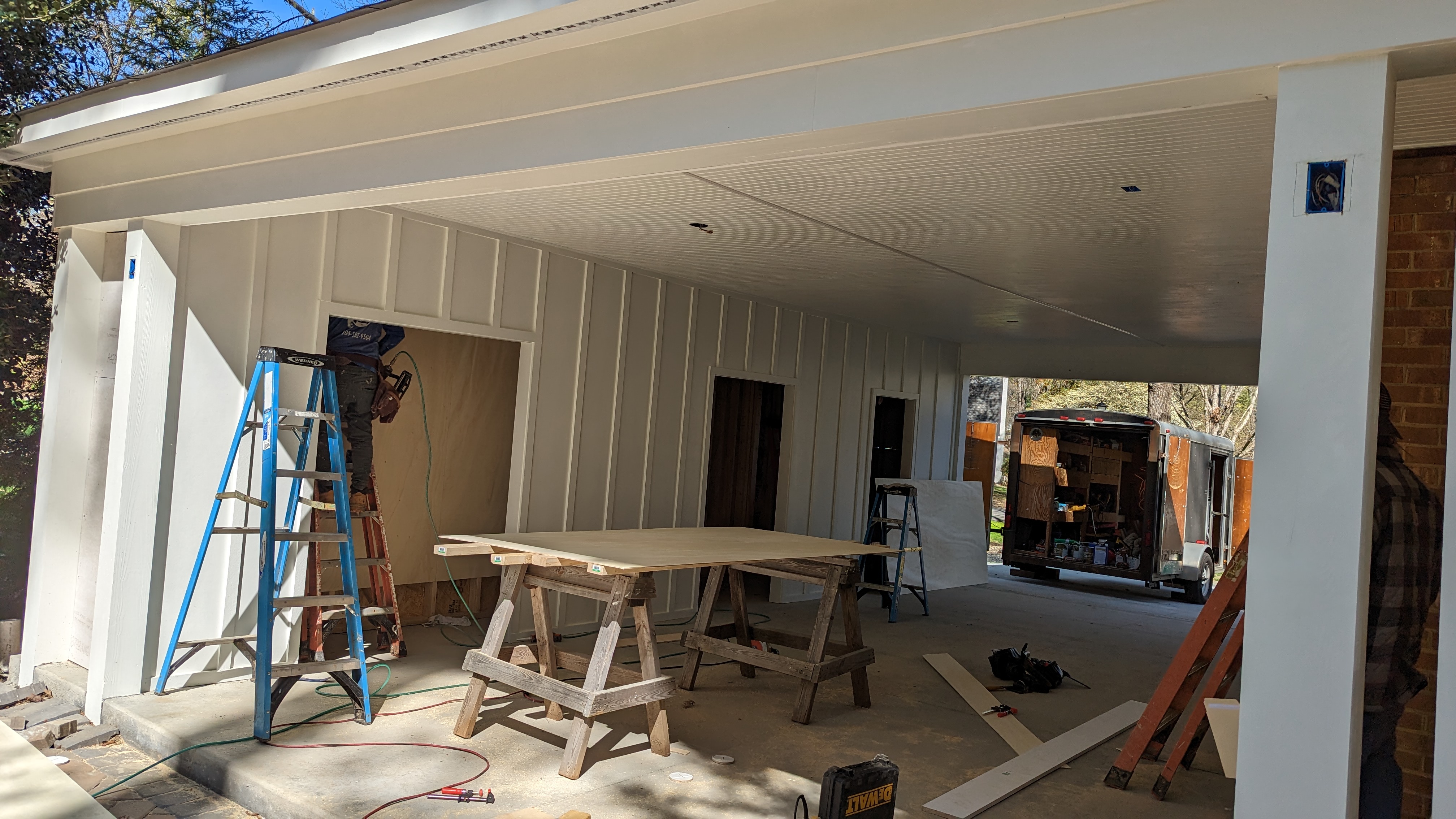 The crew installs the carport’s finished ceiling and storage-wall details.