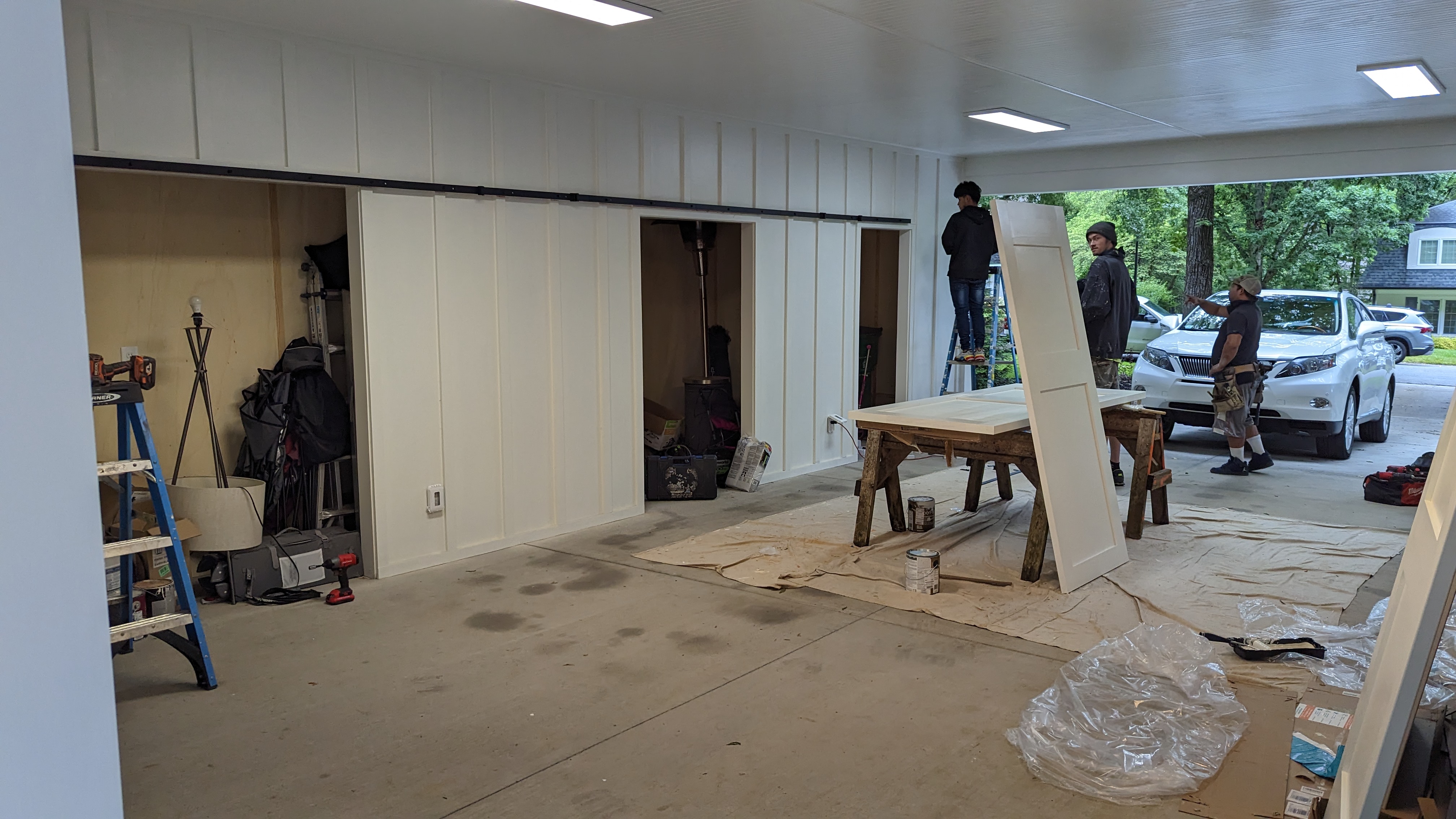 The crew hangs the sliding barn doors to complete the carport storage.